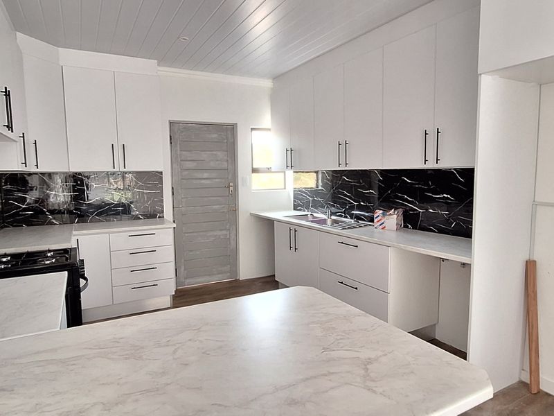 Modern kitchen featuring white cabinetry, black marble-look splashbacks, marble-effect countertops, and a gas stove, offering a clean and functional workspace.