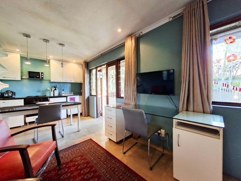 Open-plan living and kitchen area featuring built-in cabinetry, integrated appliances, tiled flooring, and direct access to the exterior through sliding glass doors.