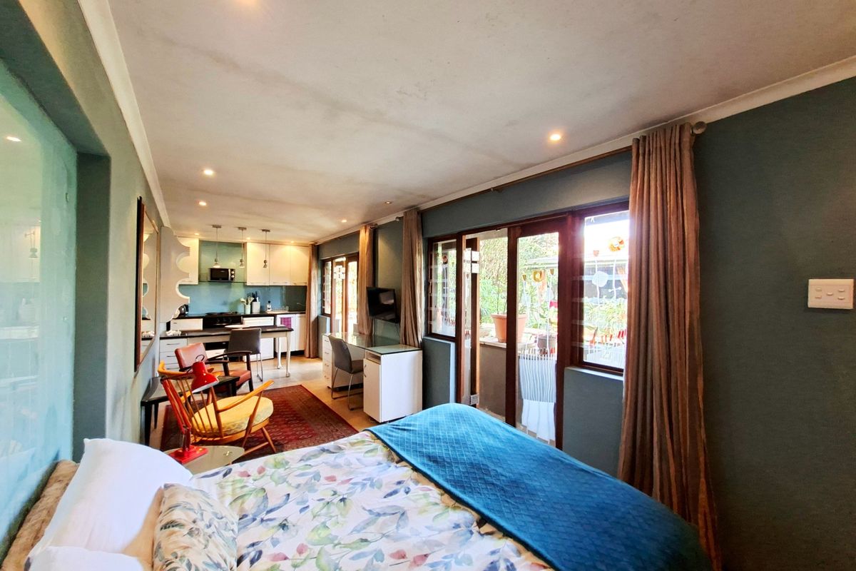 Open-plan bedroom and kitchen area featuring sliding glass doors to the exterior, recessed lighting, and built-in kitchen cabinetry.