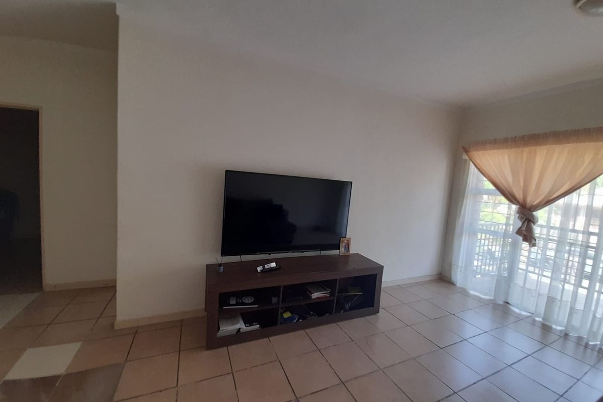 A living room area featuring tiled flooring and a sliding glass door leading to an outdoor space.