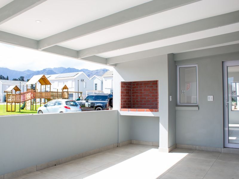 A covered patio featuring a built-in brick braai, tiled flooring, and modern aluminium fixtures, offering an open view of the surrounding residential area.