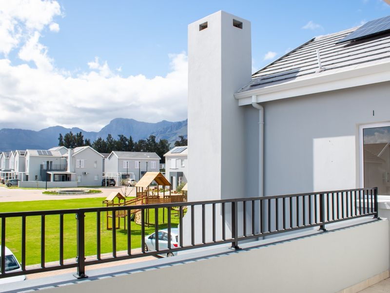 A clean, modern balcony featuring a metal balustrade and chimney stack, offering views over the estate grounds and surrounding mountains.