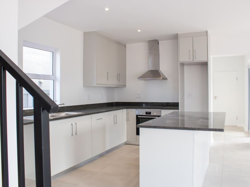 Modern kitchen featuring white cabinetry, granite countertops, stainless steel appliances, and tiled flooring in an open-plan layout.
