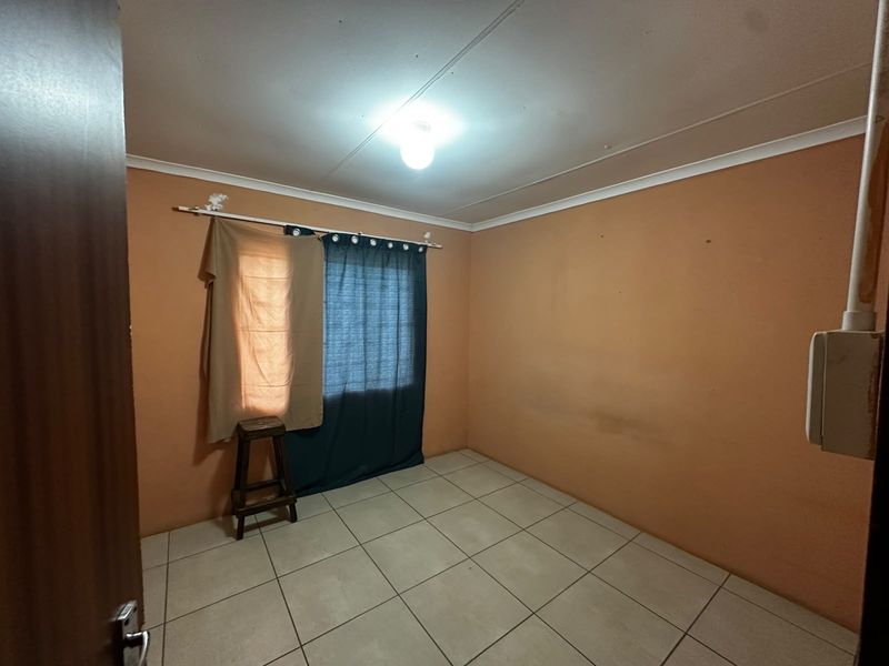 An empty bedroom featuring tiled flooring and plain walls, presenting a blank canvas ready for renovation or redecoration.