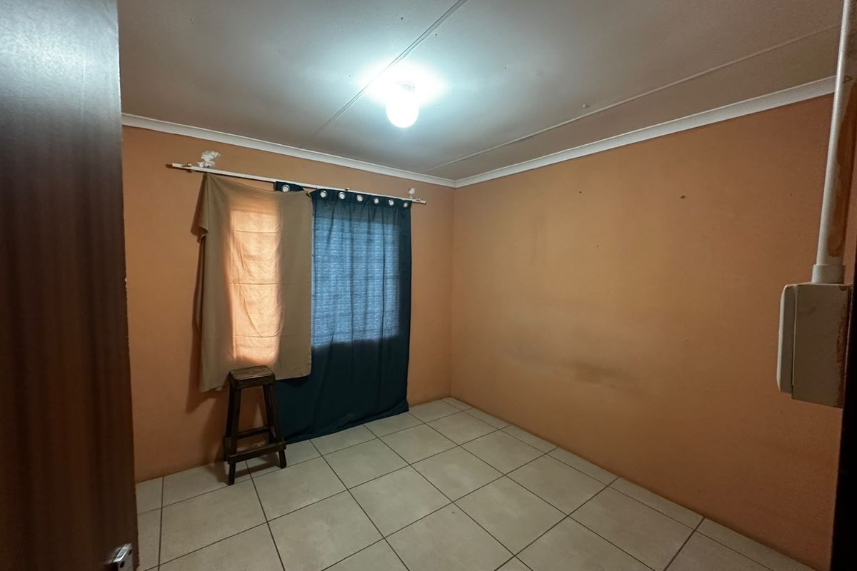An empty bedroom featuring tiled flooring and plain walls, presenting a blank canvas ready for renovation or redecoration.