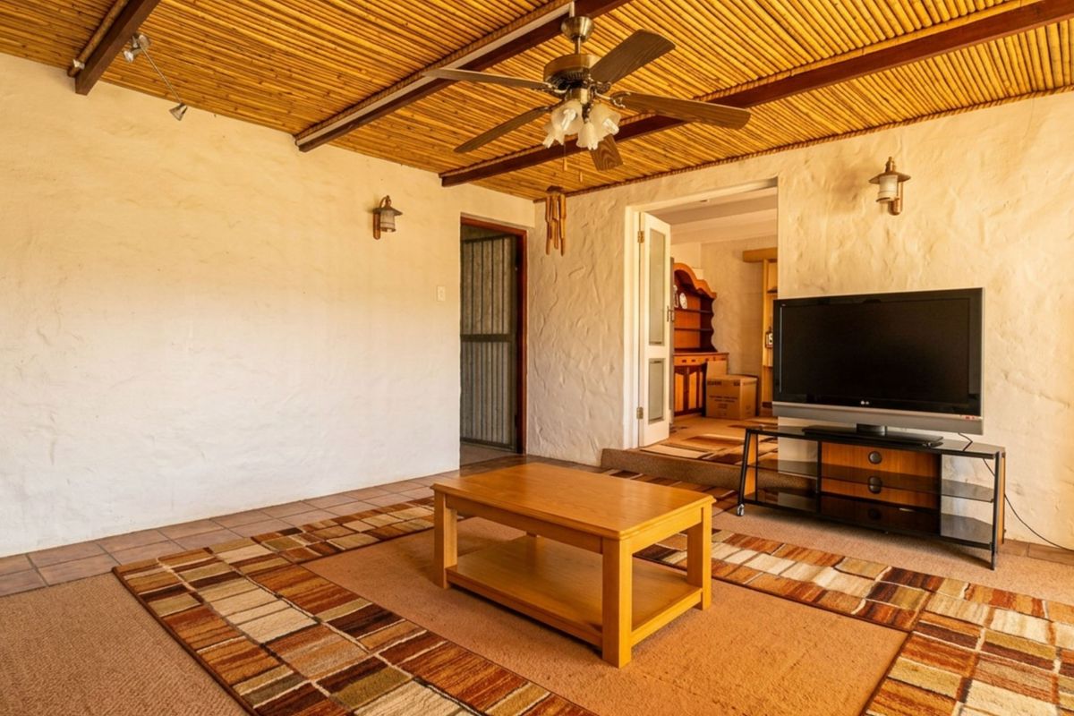 Living room featuring a rustic bamboo ceiling, ceiling fan, wall sconces, and tiled flooring, with access to an adjacent room.