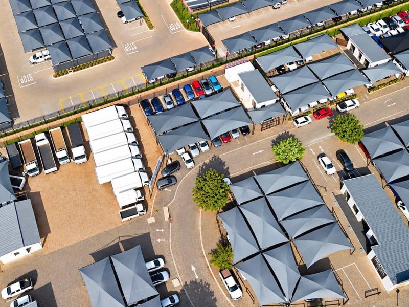 Aerial view of a commercial property featuring extensive paved parking areas with shade cloth carports and multiple office or warehouse structures.