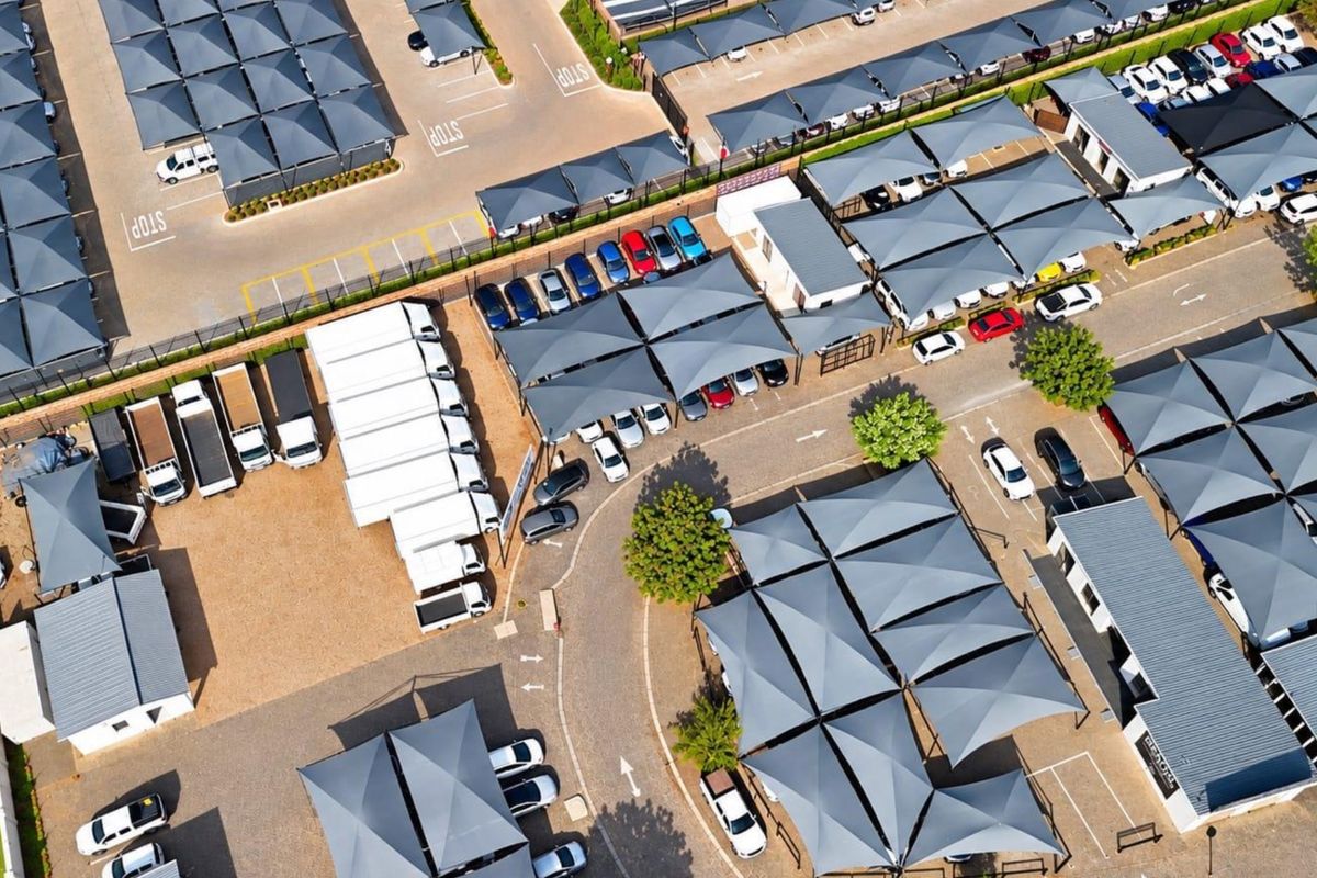 Aerial view of a commercial property featuring extensive paved parking areas with shade cloth carports and multiple office or warehouse structures.
