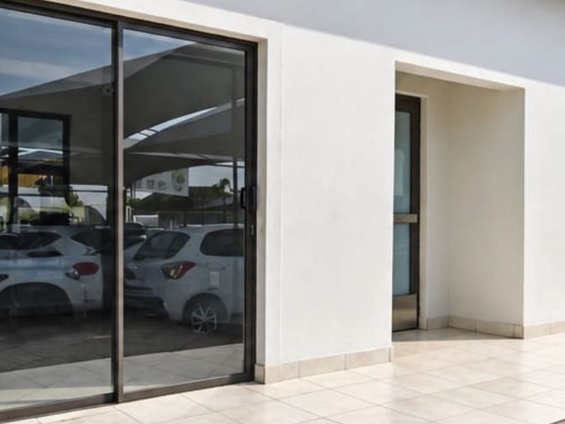A clean exterior view of a commercial building featuring tiled patio flooring and modern sliding glass doors.