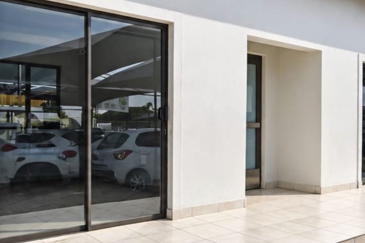 A clean exterior view of a commercial building featuring tiled patio flooring and modern sliding glass doors.