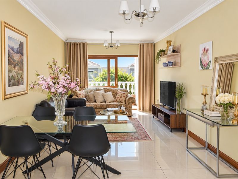 A bright open-plan living and dining area featuring polished tile flooring, crown molding, and direct access to a private balcony through sliding glass doors.