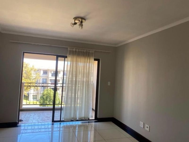 Bright and spacious living area featuring neutral tiled flooring and a large sliding glass door providing access to an outdoor balcony.