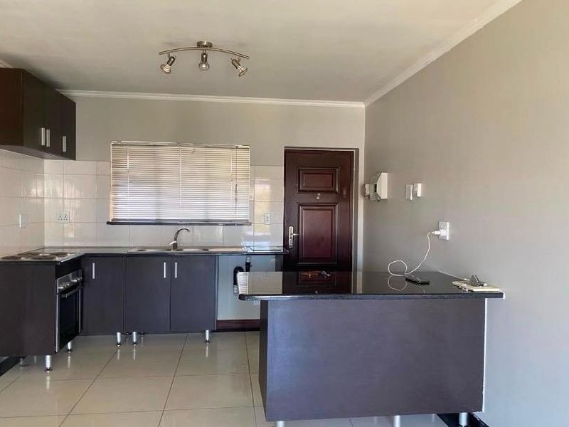 A clean, functional kitchen featuring dark cabinetry, granite countertops, built-in oven and hob, tiled flooring, and a convenient breakfast nook.