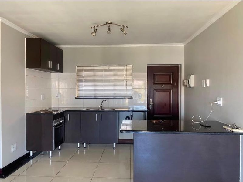 Modern kitchen featuring dark cabinetry, granite countertops, tiled flooring, and a breakfast bar, providing a clean and functional cooking space.