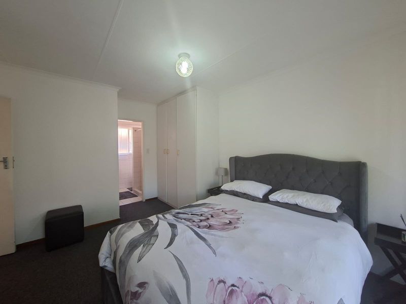 A functional bedroom featuring built-in cupboards and direct access to an en-suite bathroom, providing a practical layout for comfortable living.