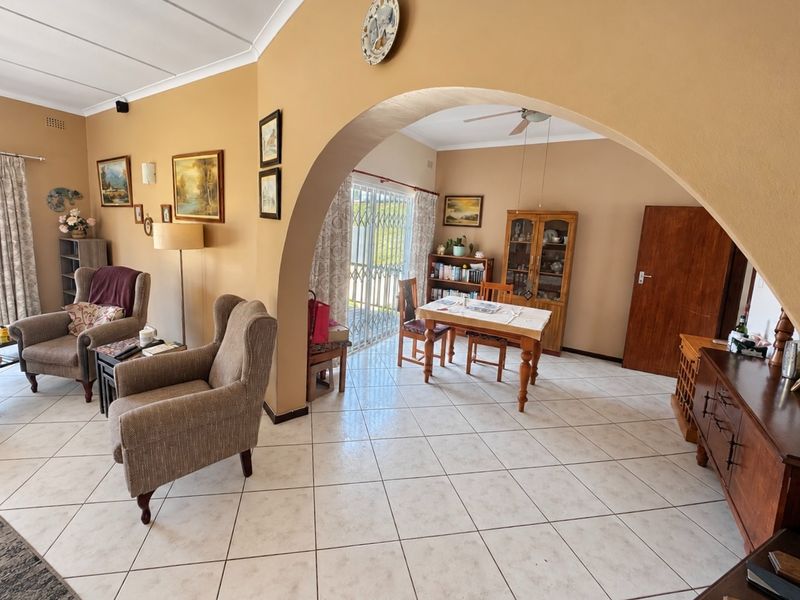 Open plan living and dining area featuring ceramic floor tiles, a distinctive arched doorway, and access to the exterior via a sliding glass door.
