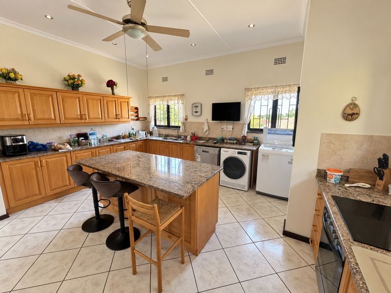 Spacious kitchen featuring wooden cabinetry, granite countertops, a central island, and tiled flooring, with integrated laundry appliances and ample storage space.