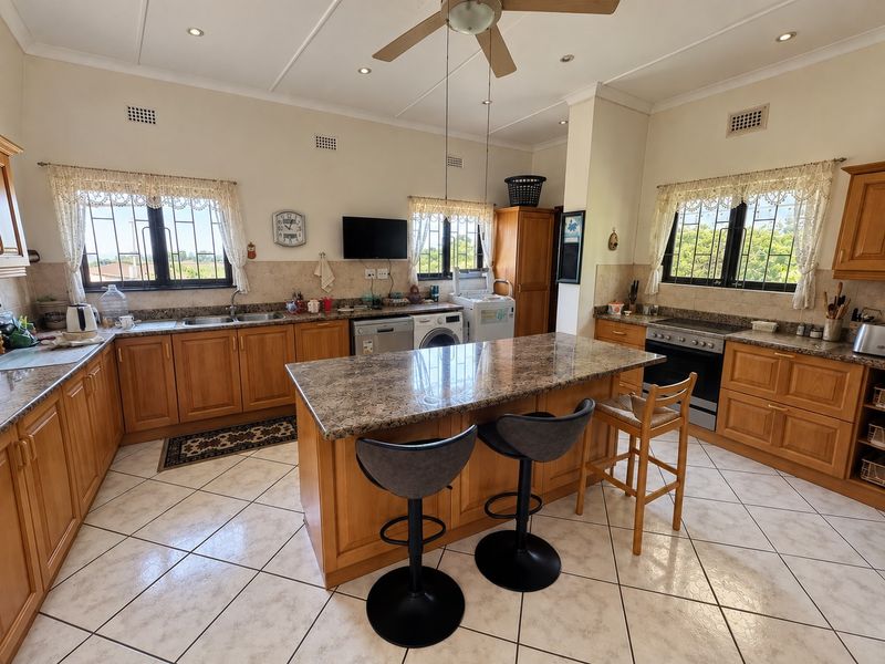 Spacious kitchen featuring wooden cabinetry, granite countertops, a central island, and tiled flooring, offering a functional layout with ample storage and workspace.