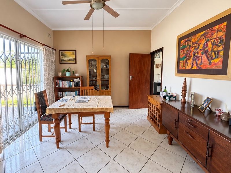 A functional dining room featuring tiled flooring, a ceiling fan, and a sliding glass door providing access to the outdoor area.