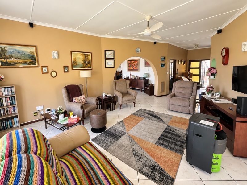 Spacious living room featuring tiled flooring, a ceiling fan, and a distinctive architectural archway leading to an adjacent area.