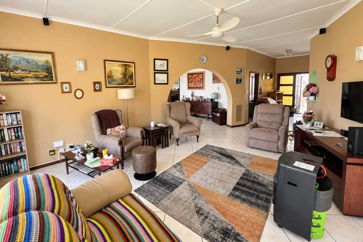 Spacious living room featuring tiled flooring, a ceiling fan, and a distinctive architectural archway leading to an adjacent area.