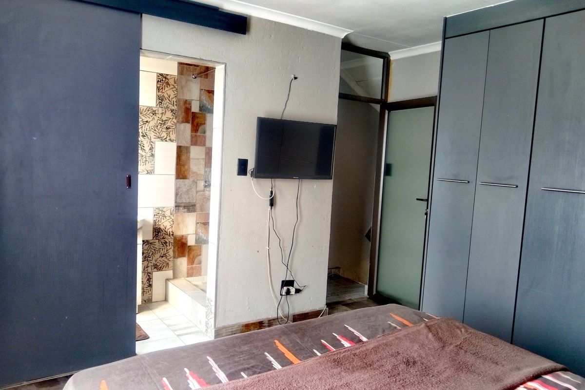 Bedroom featuring built-in cupboards and an en-suite bathroom with decorative wall tiling.