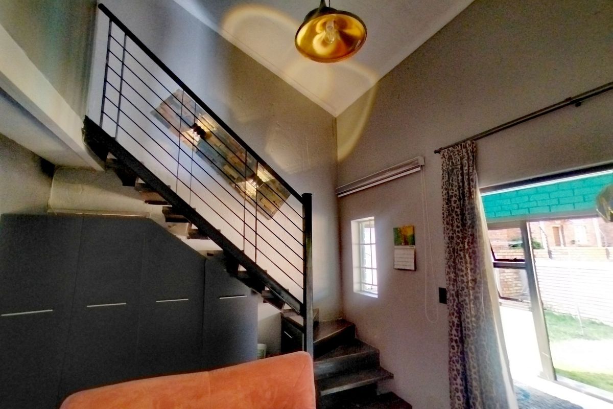 Living area featuring a modern staircase with metal balustrade, high ceilings, and direct access to the outdoor space through a sliding glass door.