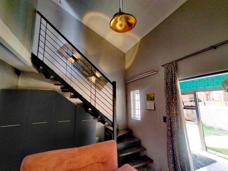 Living area featuring a modern staircase with metal balustrade, high ceilings, and direct access to the outdoor space through a sliding glass door.