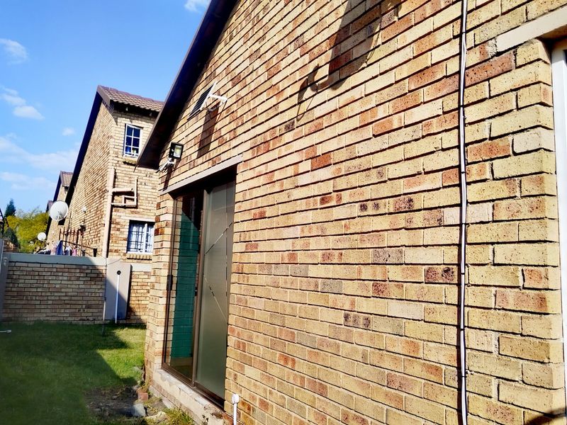 Rear exterior view of the townhouse featuring face brick construction, a sliding glass door, and a small private garden area.