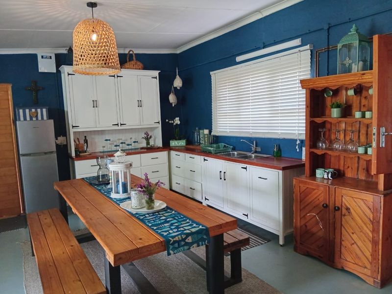 A charming kitchen featuring white built-in cabinetry, warm wooden countertops, a double basin sink, and blue accent walls.