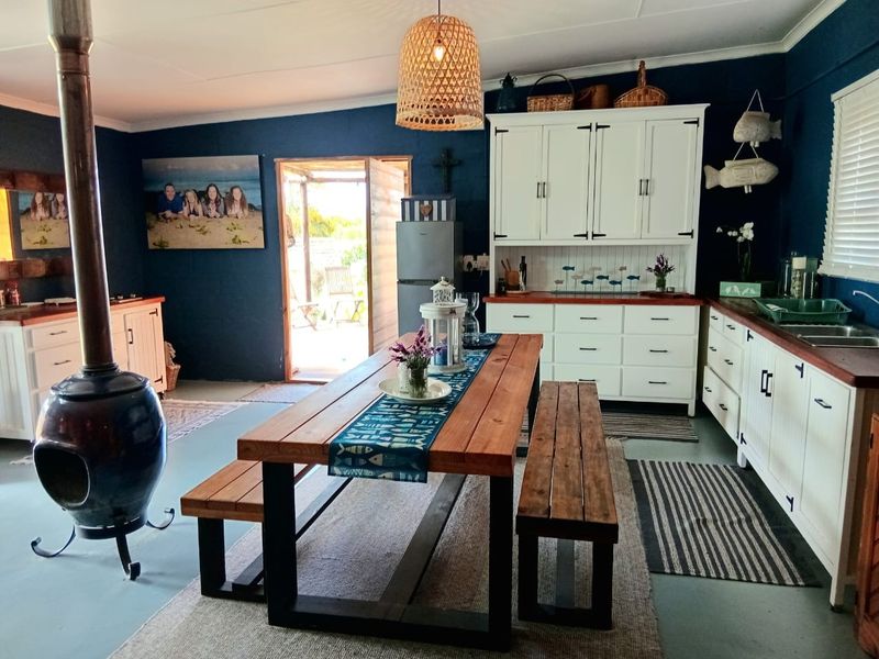 Open-plan living and kitchen area featuring a central fireplace, white cabinetry with wooden countertops, and direct access to an outdoor patio.