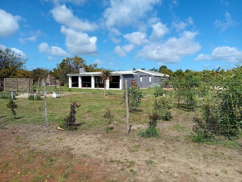 Rear view of the property featuring a covered patio, brick chimney, and expansive garden area enclosed by wire fencing.