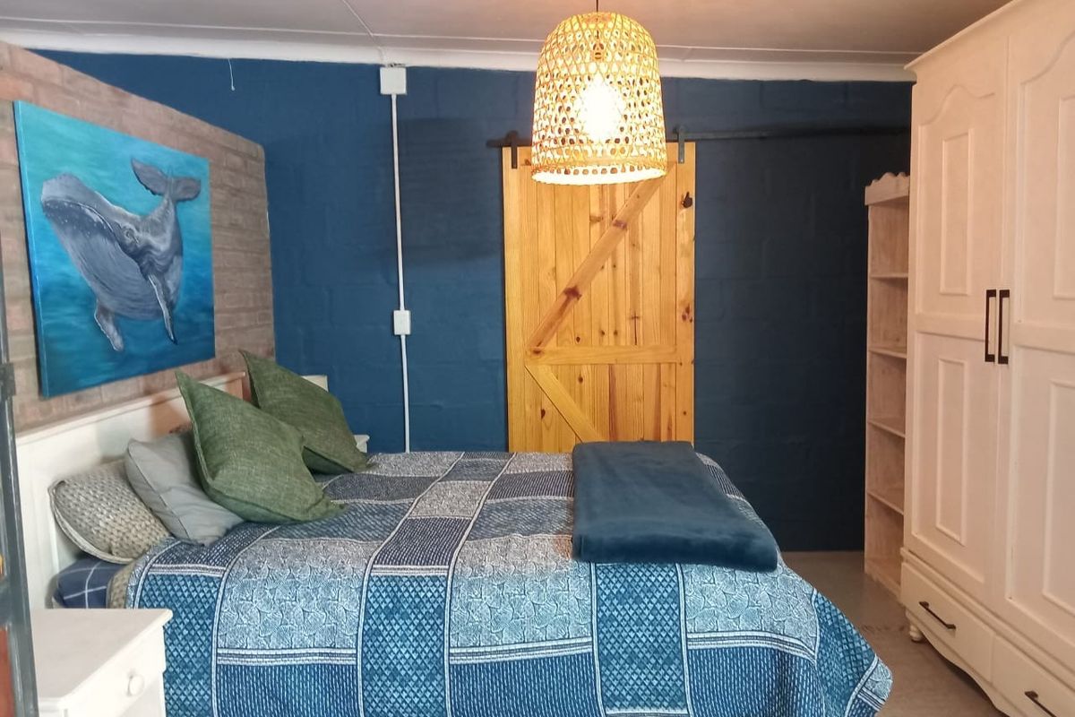 A cozy bedroom featuring a bold blue accent wall, exposed brick detailing, and a rustic sliding barn door.