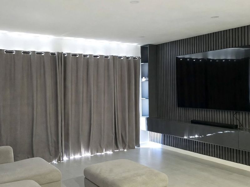 Modern living room featuring a stylish slatted timber feature wall with a built-in floating media console and recessed ceiling lighting.
