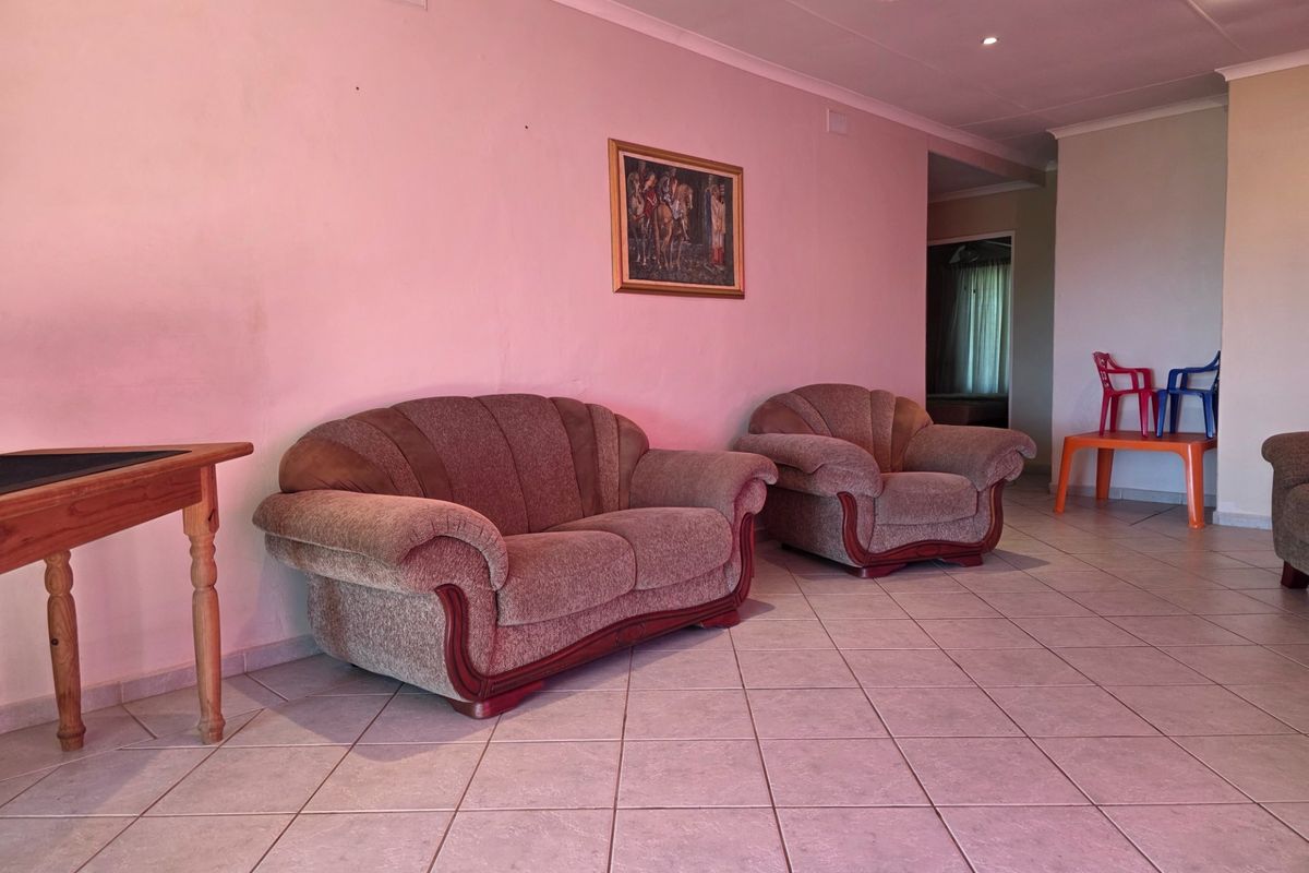 A spacious living area featuring neutral tiled flooring, coved ceilings, and recessed lighting, providing a blank canvas for modern interior updates.