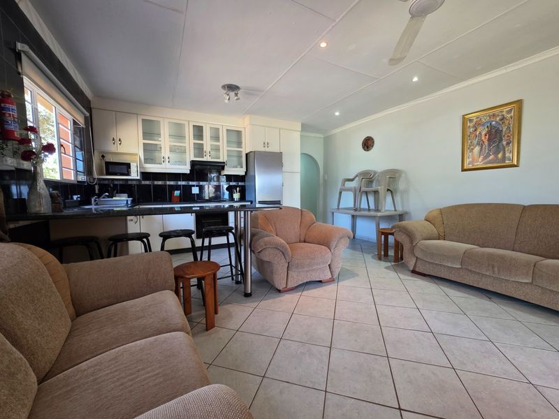 Open-plan kitchen and living area featuring tiled flooring, built-in cabinetry with granite countertops, and integrated kitchen appliances.