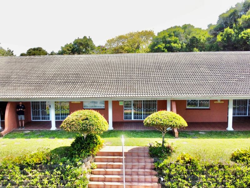 A rear view of the house featuring a long covered patio, tiled staircase, and established garden surroundings.