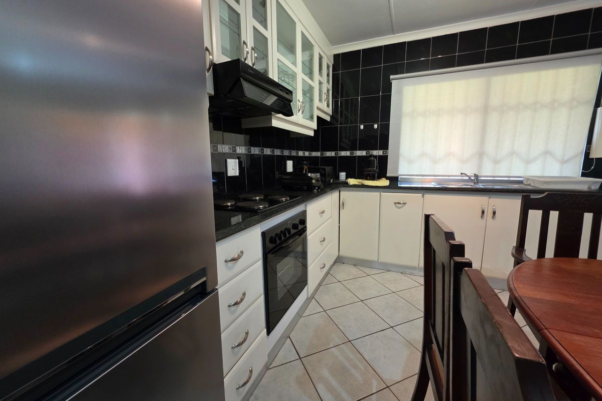 A functional kitchen featuring white cabinetry, black granite countertops, a built-in oven with hob, and a tiled backsplash.