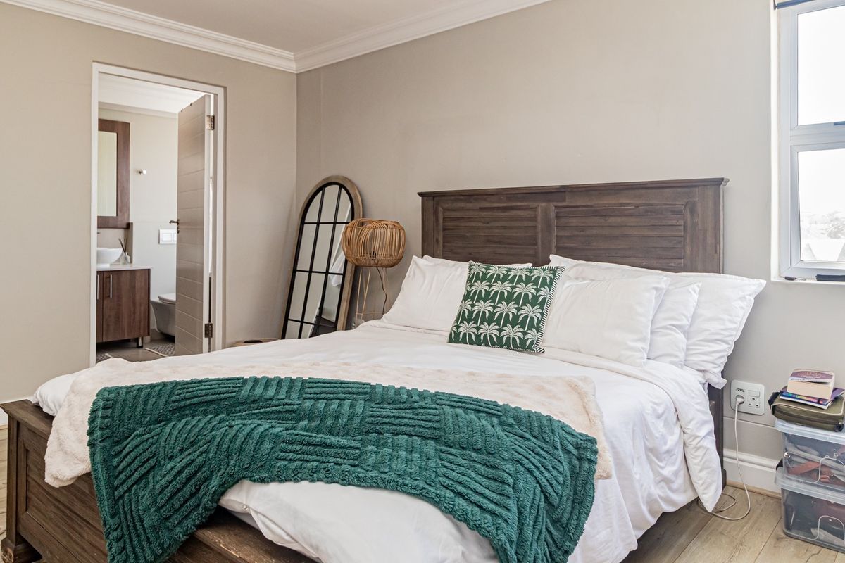 A well-maintained bedroom featuring crown molding, baseboards, and a view into the adjacent bathroom.