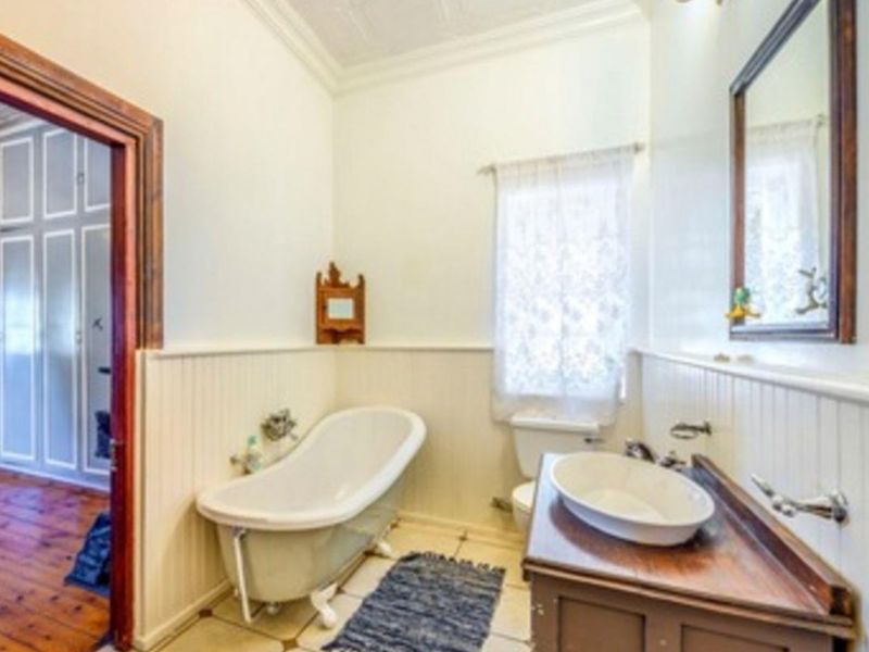 A classic bathroom featuring a clawfoot bathtub, vessel sink vanity, and charming beadboard wainscoting, offering a traditional aesthetic with potential for modern updates.