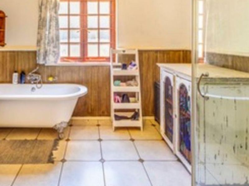 A bathroom featuring a classic clawfoot bathtub, timber wall paneling, tiled flooring, and a separate glass shower enclosure.