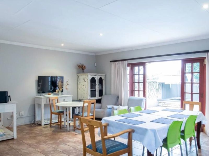 Spacious living and dining area featuring tiled flooring, recessed lighting, and double french doors providing direct access to the outdoor patio area.