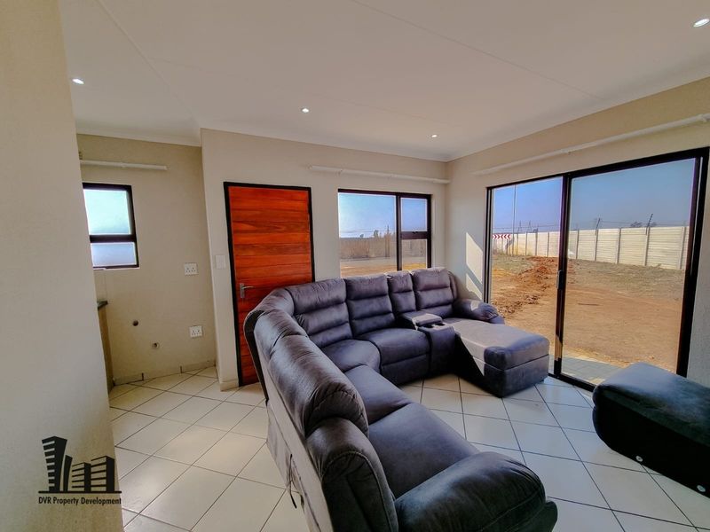 A bright living room featuring tiled flooring, recessed downlights, and large sliding glass doors providing access to the exterior.
