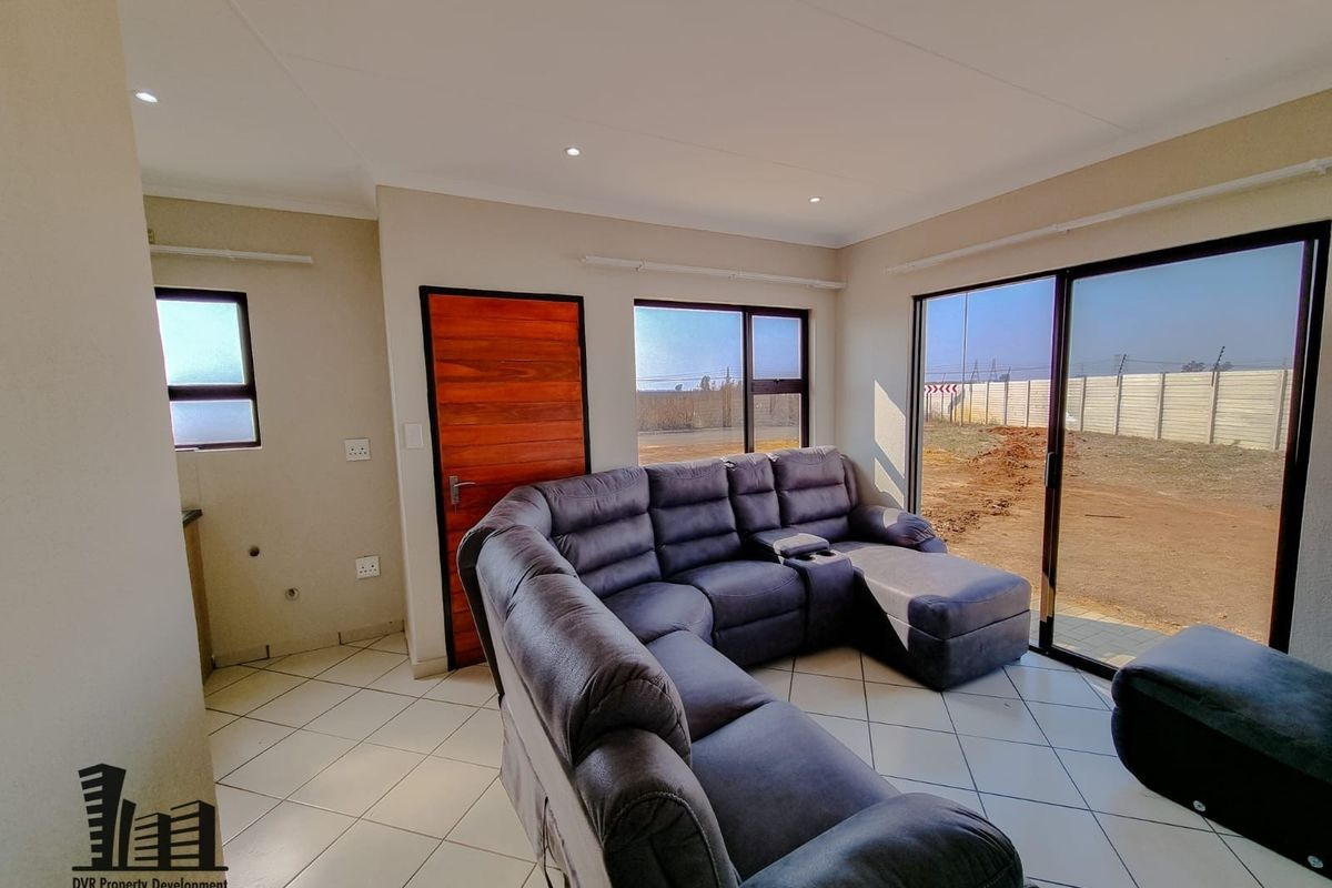 A bright living room featuring tiled flooring, recessed downlights, and large sliding glass doors providing access to the exterior.