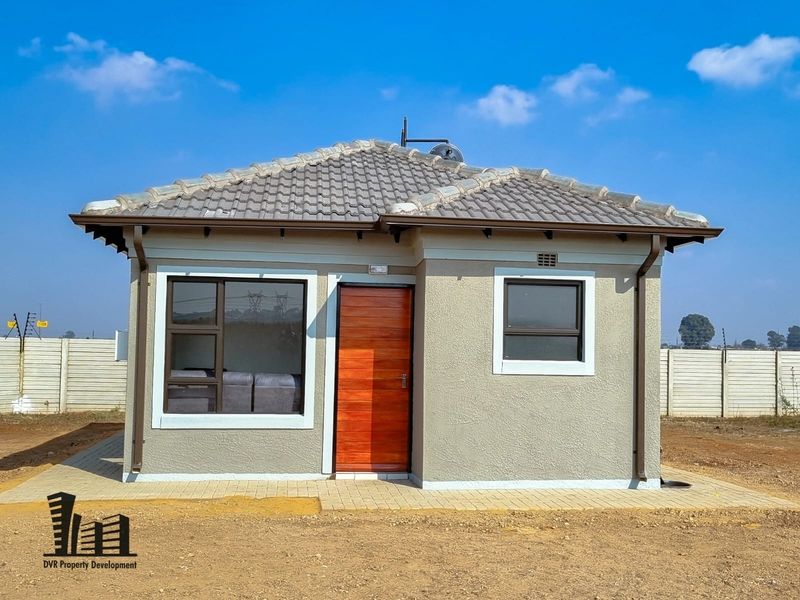 A modern, well-maintained single-story house featuring a tiled roof, aluminium window frames, and a timber front door with paved exterior access.