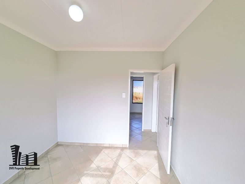 A clean, empty bedroom featuring neutral wall paint, tiled flooring, and a coved ceiling, offering a blank canvas for personalization.