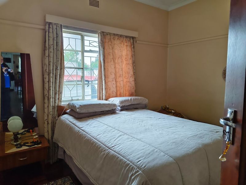 A standard bedroom featuring a window with security bars, neutral wall finishes, and traditional cornice detailing.