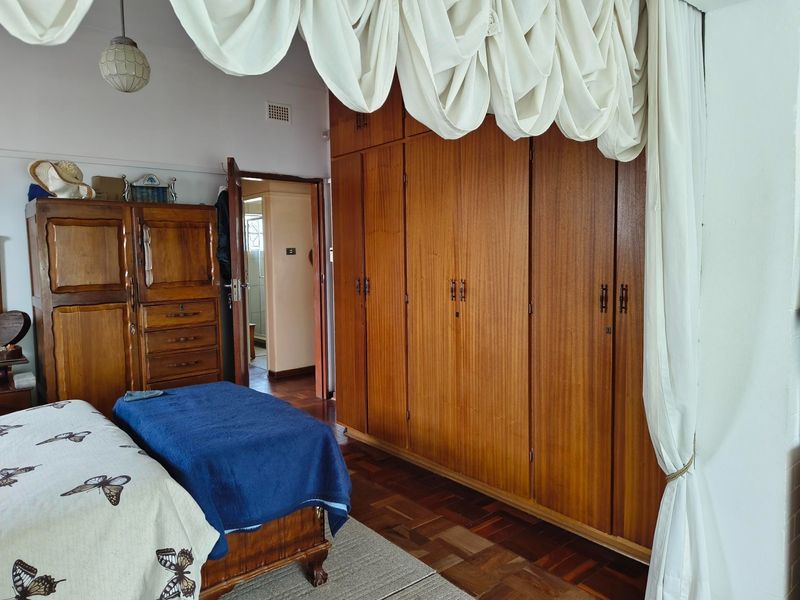 Bedroom featuring classic parquet flooring and extensive floor-to-ceiling built-in wooden cabinetry, providing ample storage space.