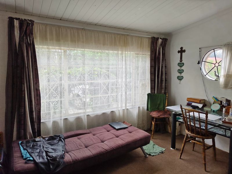 A bedroom featuring a large window, a unique circular window, and a timber ceiling, offering natural light and a cozy atmosphere.