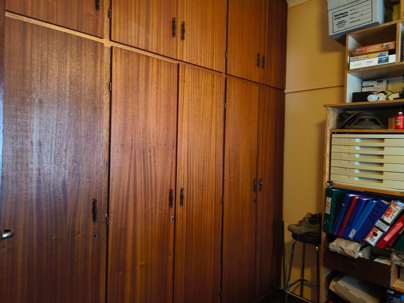 A bedroom featuring extensive floor-to-ceiling wooden built-in cupboards and overhead storage units, providing ample integrated storage space.
